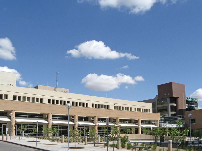 Fachada del Hospital de la Universidad de Nuevo México, en Albuquerque, bajo un cielo azul con nubes