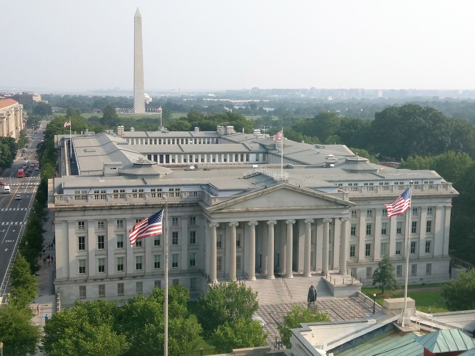 Fachada con columnas del edificio del Departamento del Tesoro en Washington, con el Monumento a Washington al fondo